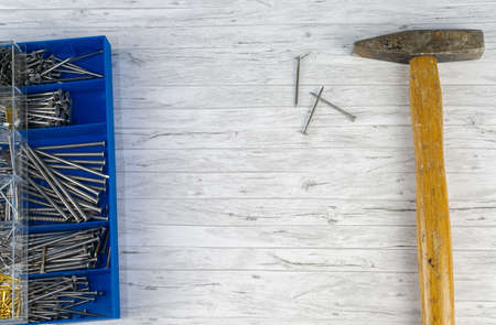 Hammer and a blue box with nails on white wood background, copy spaceの写真素材