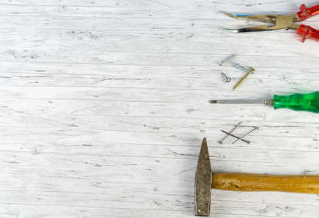 Hand tools on a white wooden background, hammer with nails and a screwdriver with different screws and pliers, copy spaceの写真素材