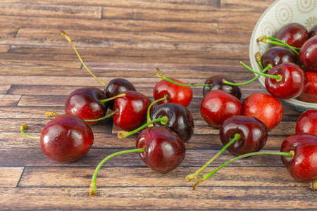 Fresh sweet cherries in a cup, dark brown wood background with copy spaceの写真素材