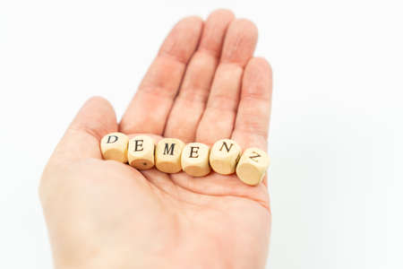 Hand with letter cubes and the german word for dementia, white backgroundの写真素材