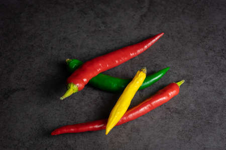 A group of fresh red, green, and yellow chili pepper on black background, copy space and top viewの写真素材