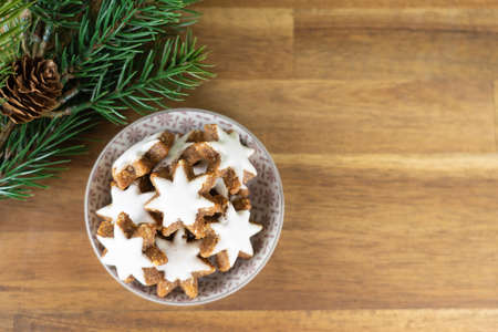 A cup with christmas biscuits on a wooden table and with fir branches, top viewの写真素材