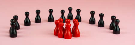 Black toy figures in a semicircle around red toy figures, banner and pink backgroundの写真素材