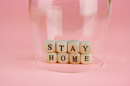 The words stay home under a drinking glass, pink backgroundの写真素材