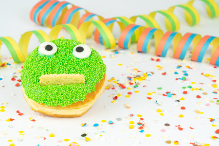 Funny green face cake with confetti and streamers, white backgroundの写真素材