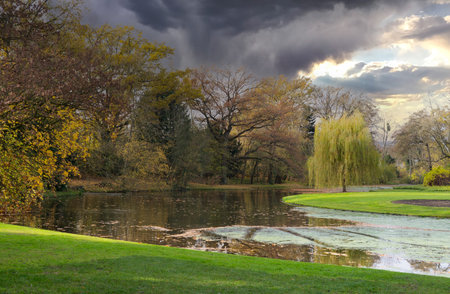Beautiful autumn scene with a dramatic sky at a lake in the park in the Karlsaue in Kassel, Germanyの写真素材