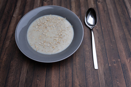 A plate of porridge with a spoon on a wooden table, copy spaceの写真素材