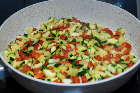 Zucchini and red peppers in pieces in a panの写真素材