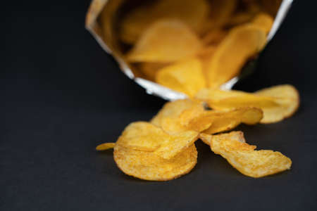 Opened bag of chips on black background, copy spaceの写真素材