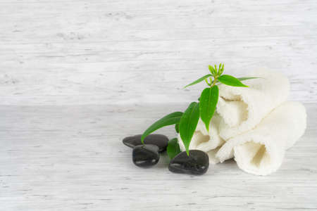 Three white towels with green plant branch and stones, copy spaceの写真素材