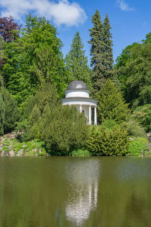 Small white temple in a park in front of a pondの写真素材