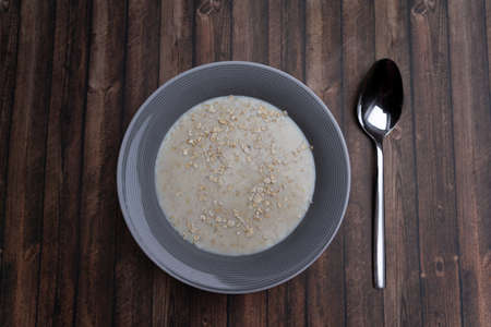 A plate of porridge with a spoon on a wooden table, top view and copy spaceの写真素材