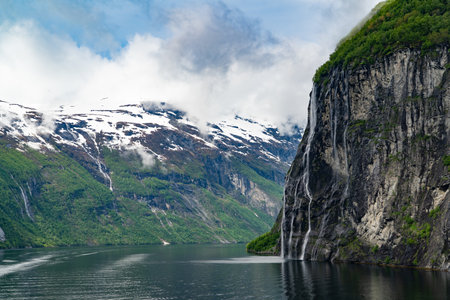 Beautiful landscape with snowy mountain peaks and waterfalls in Geiranger fjord, Norwayの写真素材