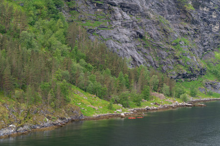 Beautiful Geiranger Fjord in Norway with on which people paddle in two canoesの写真素材