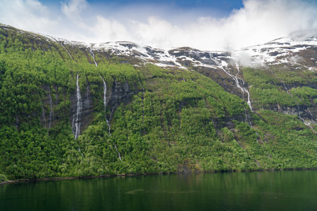 Beautiful landscape with snowy mountain peaks and waterfalls in Geiranger fjord, Norwayの写真素材