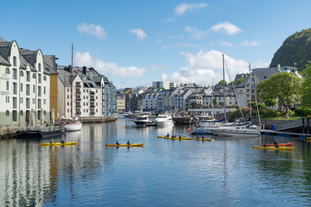People ride small canoes across the channel in Alesund, Norway, June 05th 2022の写真素材