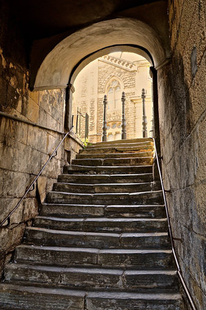 Old Roman steps under a covered stone archway tunnel, in the historic English town of Bath.