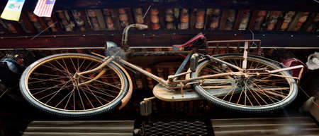 An old vintage bicycle suspended from the ceiling of a rustic wooden building.の写真素材