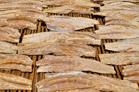 Rows of fish drying in the sun laid out on a bamboo slatted platform.の写真素材