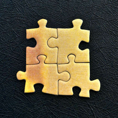 Four yellow jigsaw pieces isolated on a textured black background.の写真素材