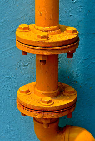 Junctions of two Heavy duty yellow, metal water pipes joined by nuts and bolts. の写真素材