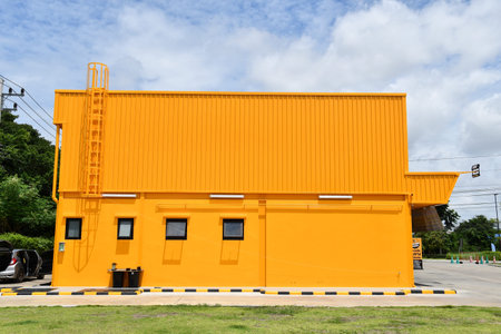 Side view of a large yellow building against a cloudy sky background.の写真素材
