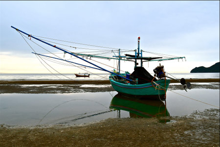 Traditional Asian wooden fishing boats moored during low tide.の写真素材
