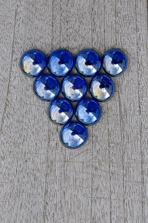Inverted triangle of iridescent blue glass beads isolated on a rustic wooden background