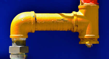 A heavy duty industrial yellow, metal water pipe isolated against a dark blue background.の写真素材