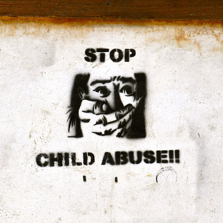 A stencilled poster stating Stop Child Abuse on a rustic stone wall in Asia. 