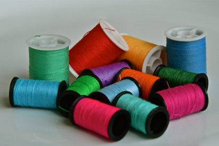 A close up perspective view of cotton bobbins of idfferent colours and sizes