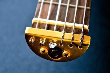 Close up view of the end of the neck of a travel guitar showing the brass fittings, strings and...