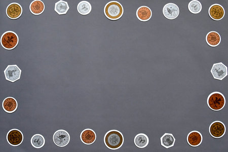 Maths concept flatlay on a grey background with copy space. Focusing on money with toy British sterling coins.の写真素材