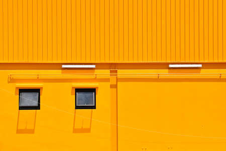 A bright yellow building built of stone and currugated iron panels. の写真素材