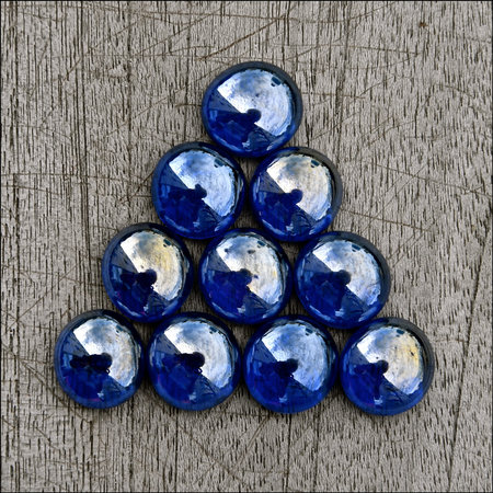 Triangle of iridescent blue glass beads isolated on a rustic wooden backgroundの写真素材