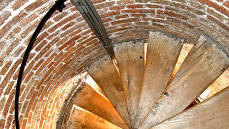 Looking down an old wooden spiral staircase in a brick circular turret in an old medieval brick...