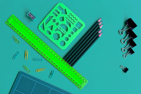 Flatlay of assorted school items of paper clips, bulldog clips, ruler, pencils, cutting boards,...
