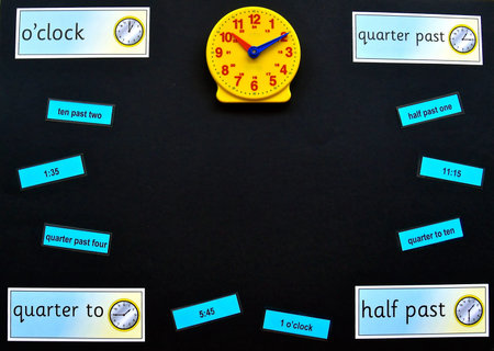 Maths concept flat lay on a black background with copyspace, focusing on time with an analogue toy...