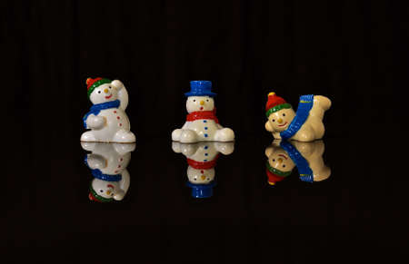 A christmas display of models of snowman on a reflective black surface.の写真素材
