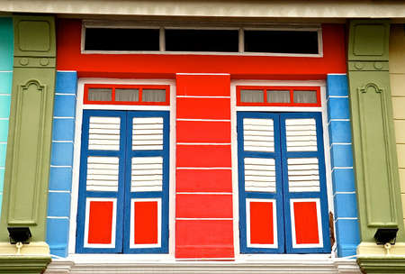 Colourful red and blue shuttered windows as found in a restored traditional chinese chop house.のeditorial素材