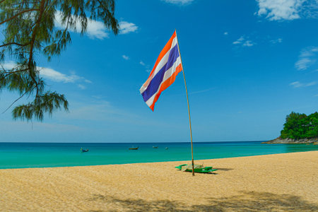 A tropical beach in Thailand with the national flag fluttering in the sea breeze, on the golden...