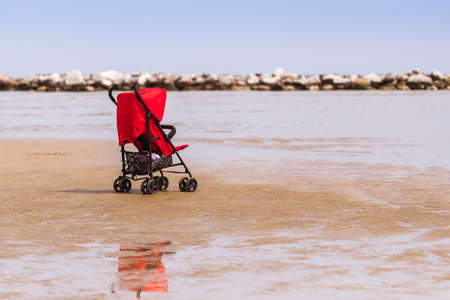 Summer vacation, red baby carriage on the sea beach, vacation with childrenの写真素材