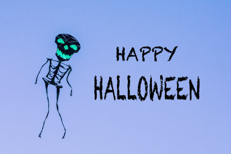 Happy Halloween greeting card. Holiday composition with text Happy Halloween, with skeleton kite on blue background. Postcard for holiday. Spooky concept. Halloween concept.の写真素材