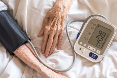 Elderly women measures her blood pressure and pulse using electronic device. Hands elderly women close up. Overhead view.の写真素材