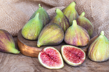 Raw sweet figs on a wooden background closeup. Red - purple e green figs. Figs whole and cut into halves. Organic gardeningの写真素材