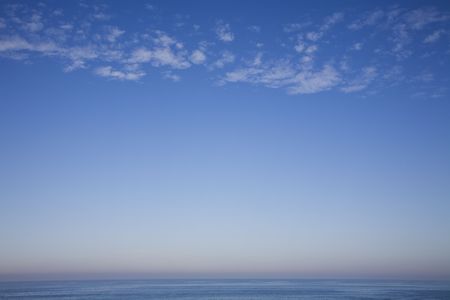 cotton wool clouds over a calm blue seaの写真素材
