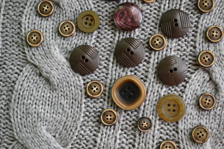Buttons on a gray knitted background. Top view. Flat lay.