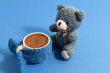 Coffee cup dressed up with knitted liner and teady bear. Blue Monday concept.の写真素材
