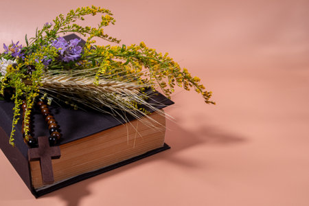 Bible with a cross and a bouquet of wildflowers. Assumption of Mary Day. Traditional herb consecration day.の写真素材