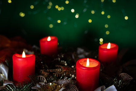 Christmas wreath with burning candles on green bokeh background.の写真素材